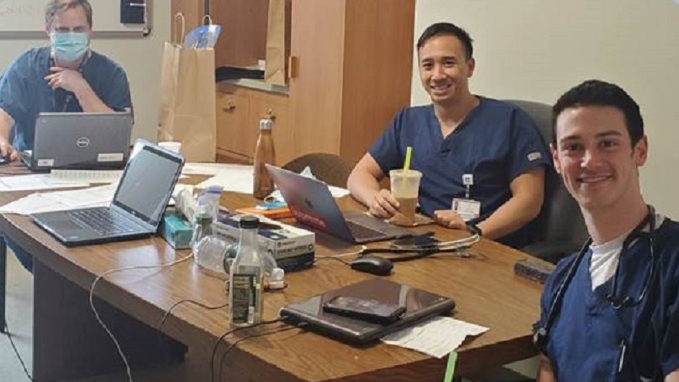 doctors sitting at table with laptops